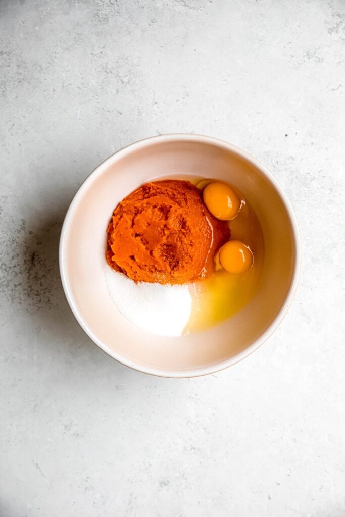 eggs, sweetener, and pumpkin puree added to a mixing bowl.