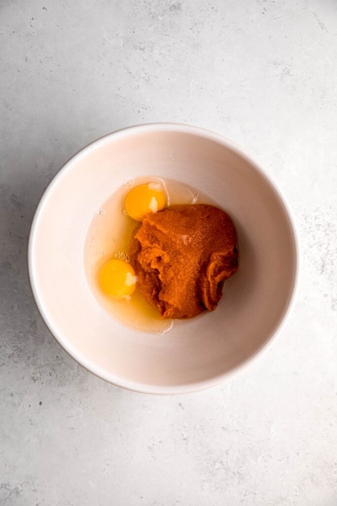 eggs and pumpkin puree added to a mixing bowl.