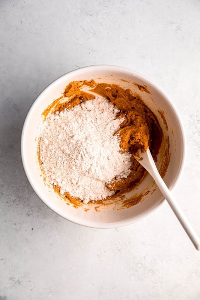 oat flour added to the bowl with the peanut butter, pumpkin, and egg mixture.