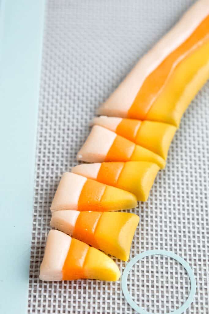 closeup shot of a line of candy corn pieces that have been cut from one of the long rainbow ropes.