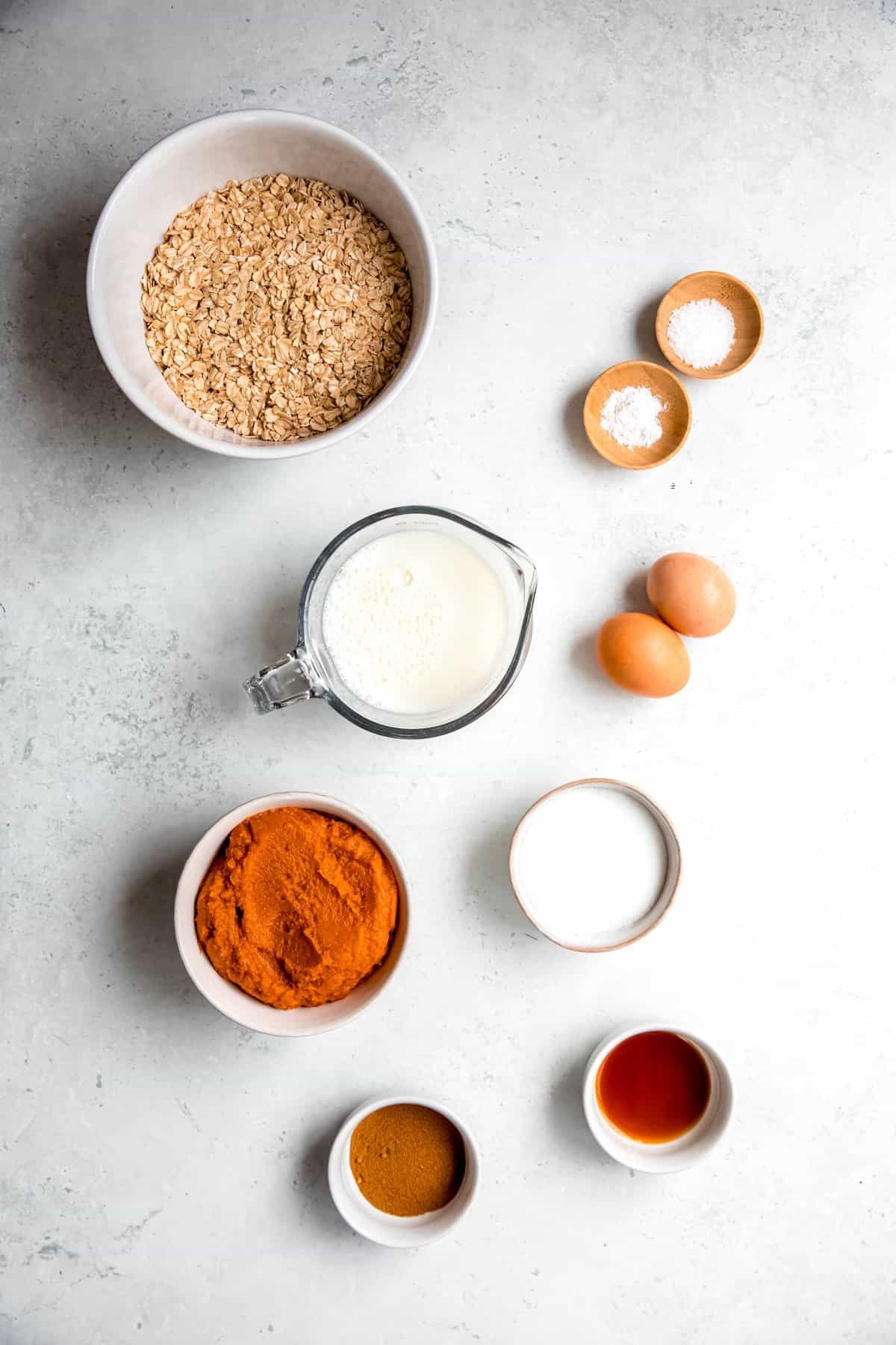 ingredients needed to make healthy pumpkin pie baked oatmeal recipe measured out on a white table.