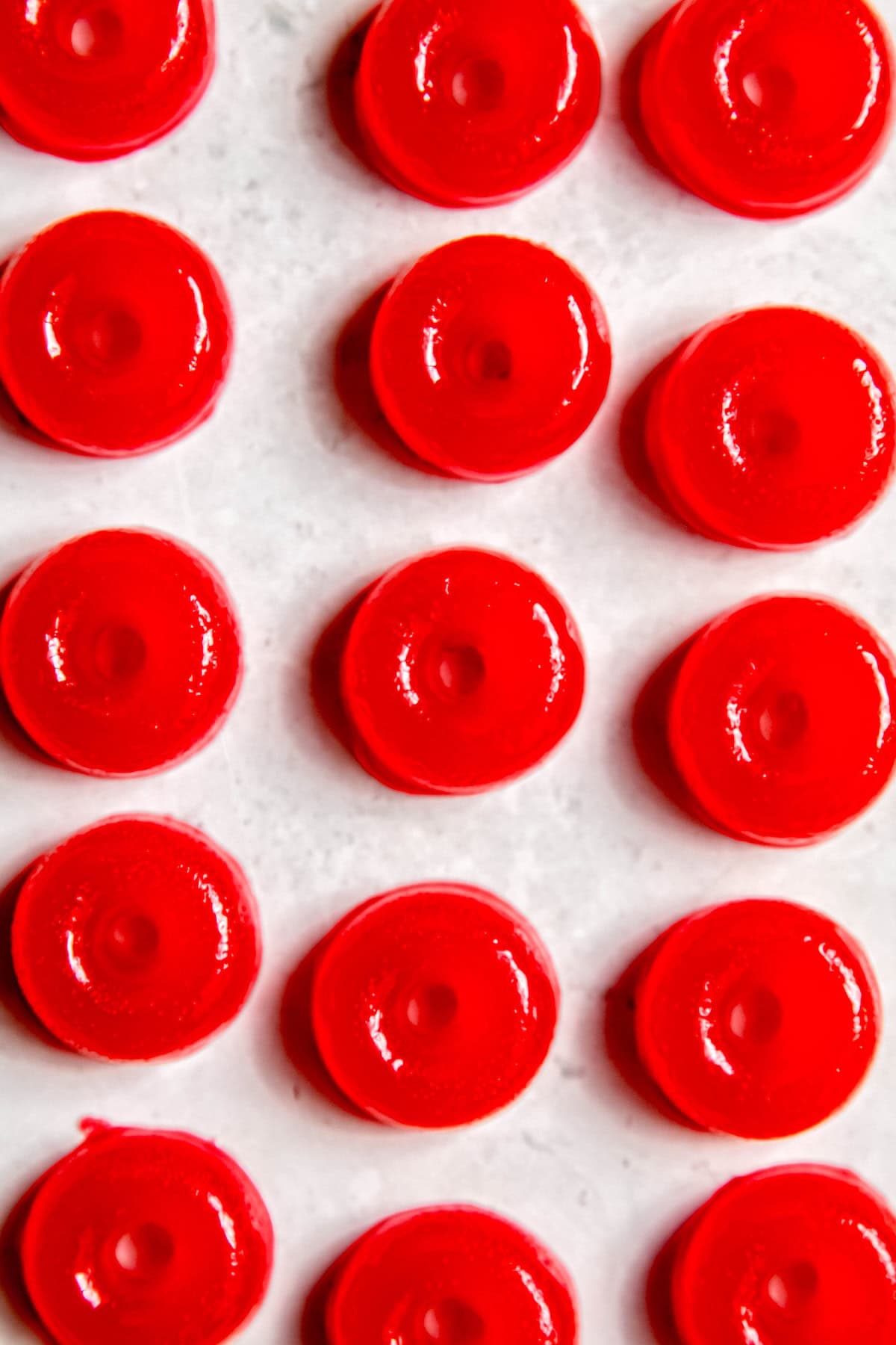 overhead shot of neat lines of homemade weed gummies made with red jello on a white table.