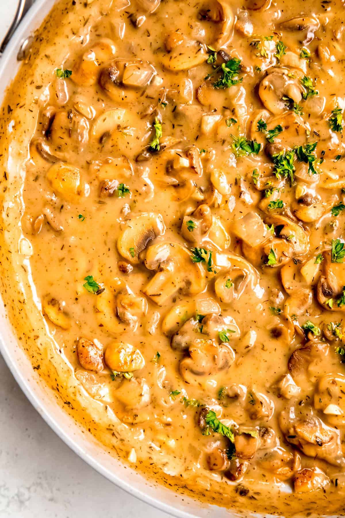 closeup overhead shot of the left side of a skillet filled with creamy mushroom gravy made with white wine.