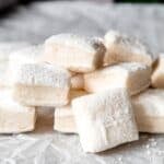 jumbled stack of fluffy vanilla marshmallows showing the vanilla bean-flecked interior and the powdered sugar exterior.