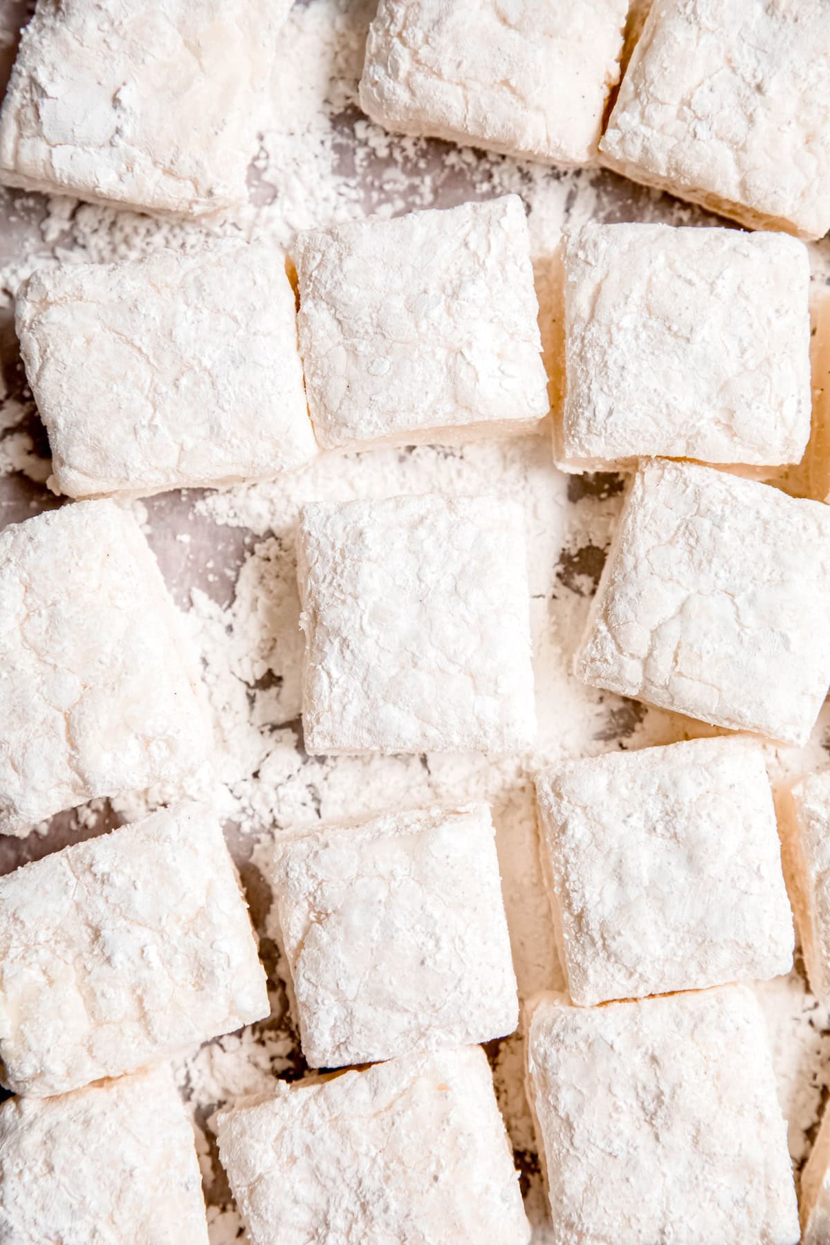 flat lay shot of easy homemade marshmallows after cutting into squares; you can see the heavily powdered surface underneath to keep them from sticking as they were cut.