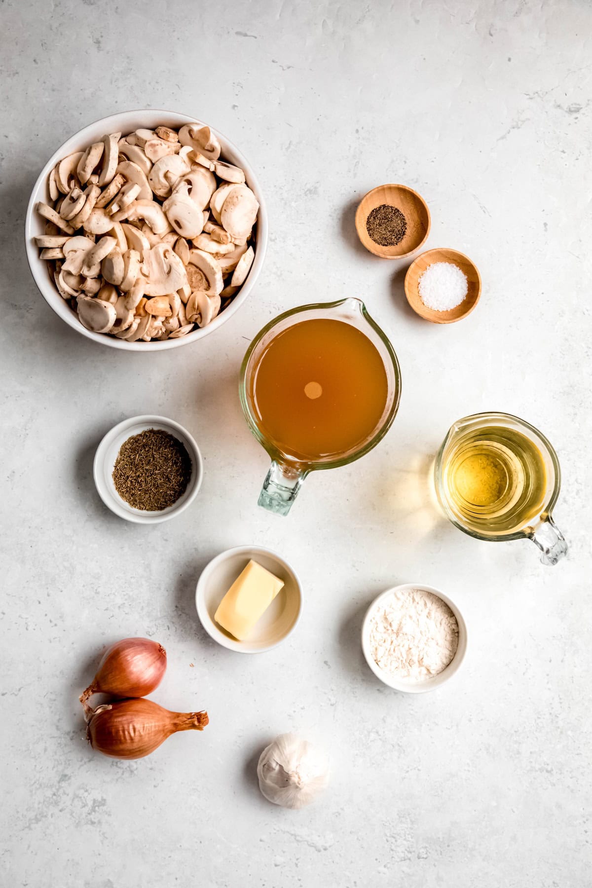 ingredients needed to make mushroom gravy measured out into containers on a white table.