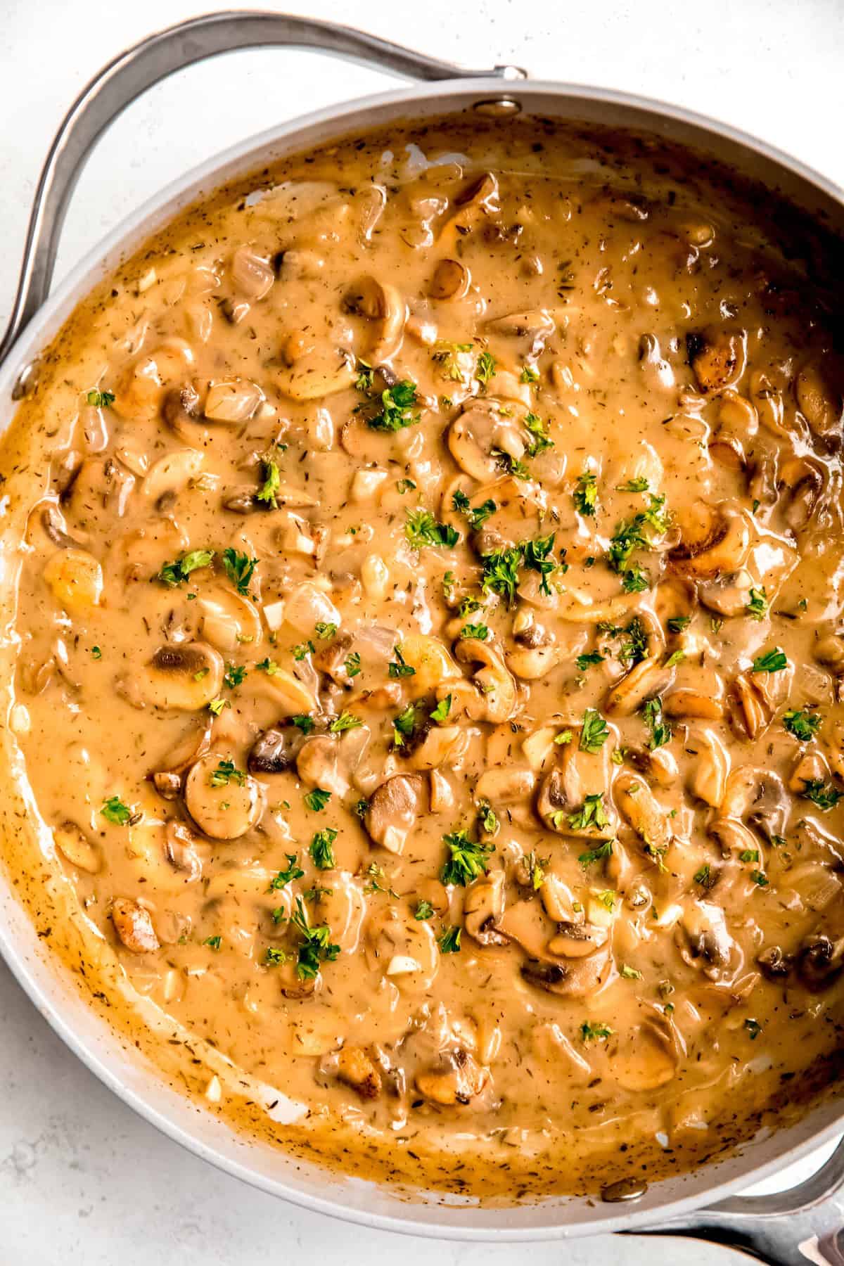 overhead shot of creamy make-ahead mushroom gravy in a skillet garnished with some chopped parsley.