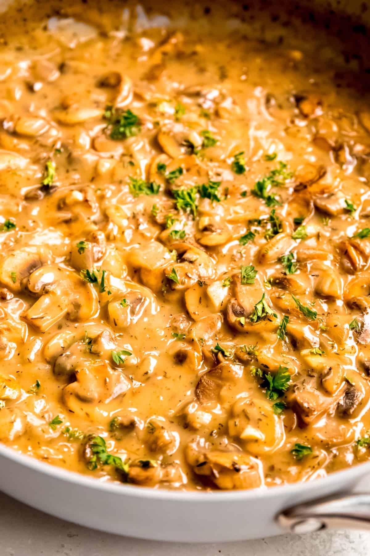 45 degree angle shot of mushroom make-ahead gravy in the skillet with a sprinkle of fresh parsley on top.