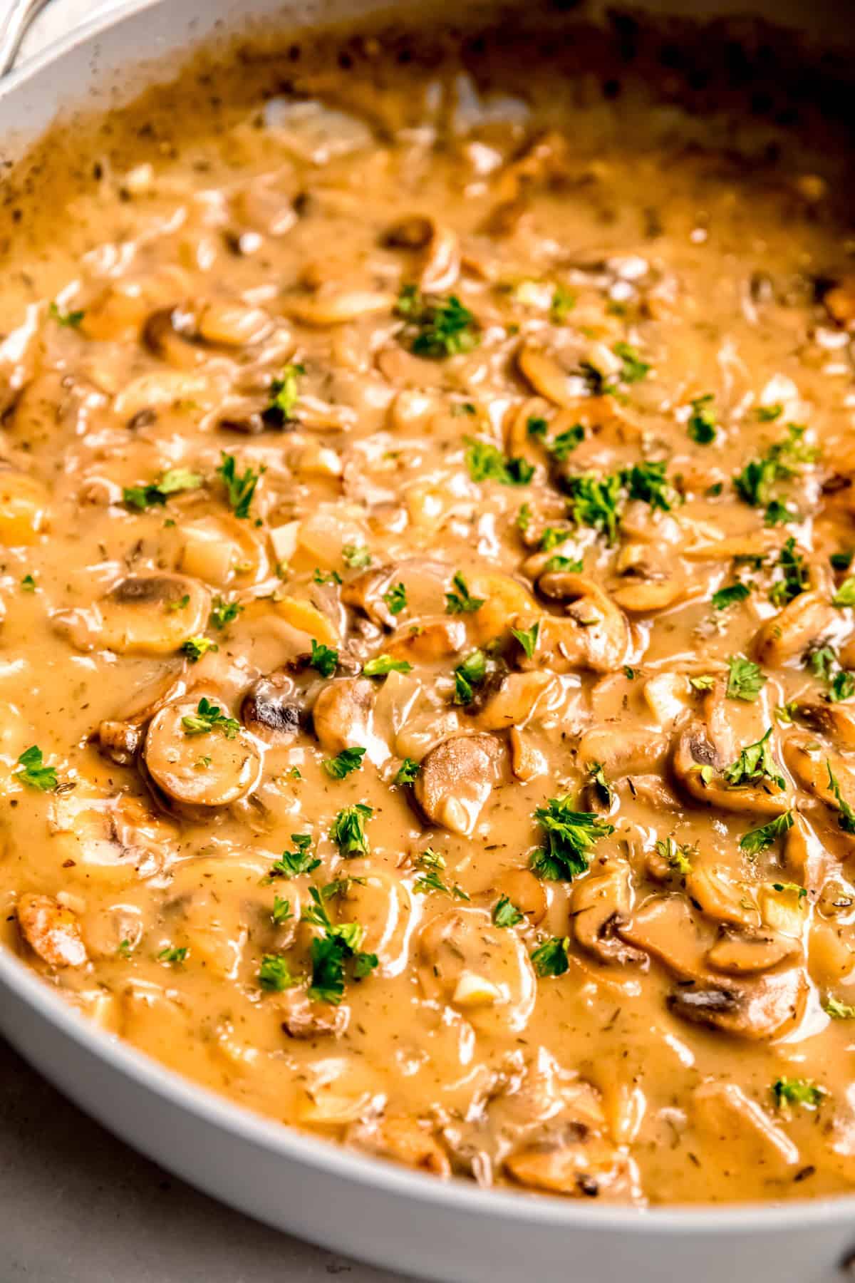 45 degree angle of vegetarian make ahead gravy with mushrooms in a skillet topped with fresh herbs.