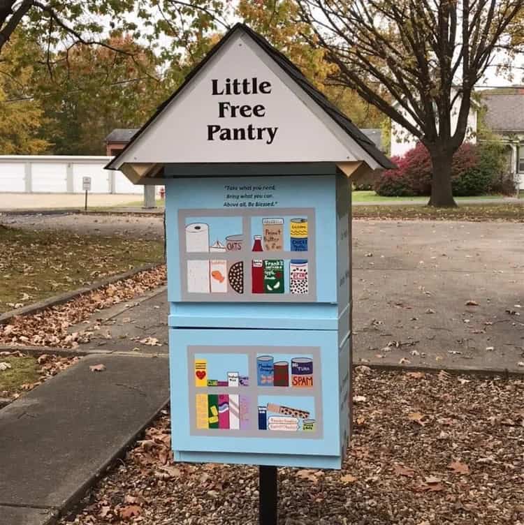 cute newspaper dispenser turned into a free pantry with a roof that says little free pantry and hand painted "windows" on the front with food stuff painted behind.