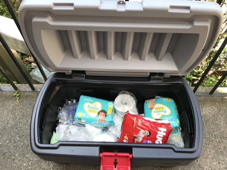 outdoor deck box set up as a free pantry with diapers, toilet paper, and baby food.