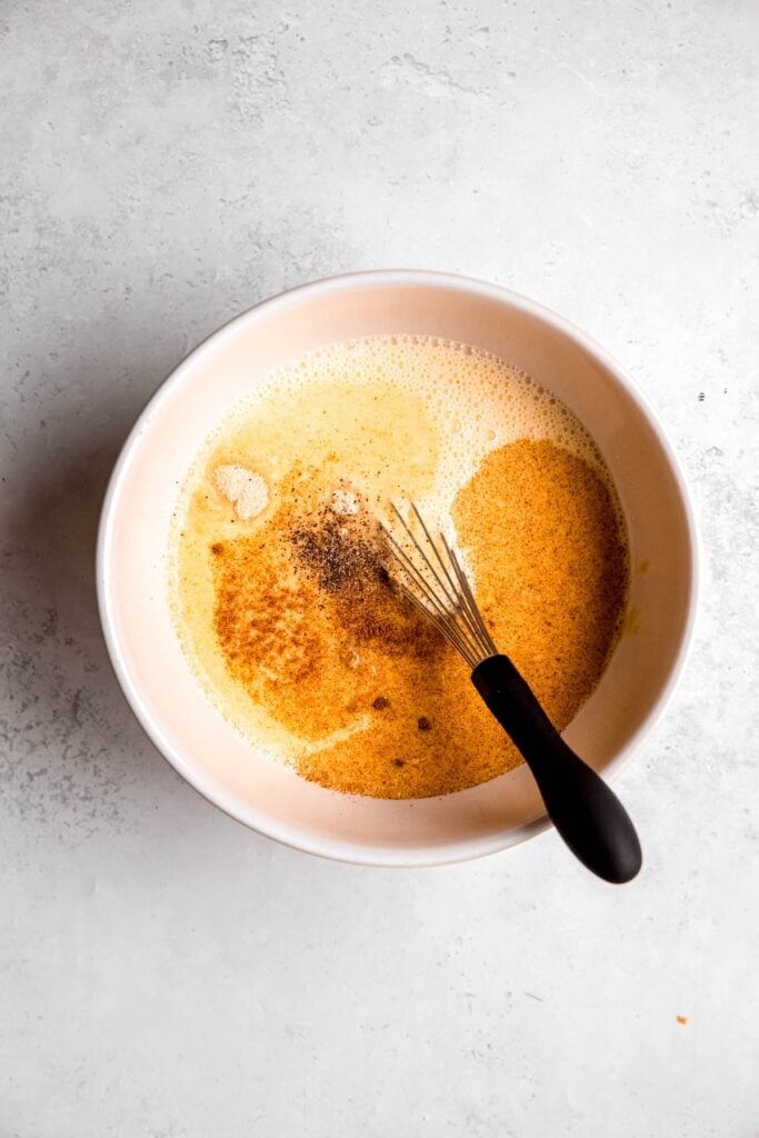spices and mustard added to the egg mixture that's been whisked.