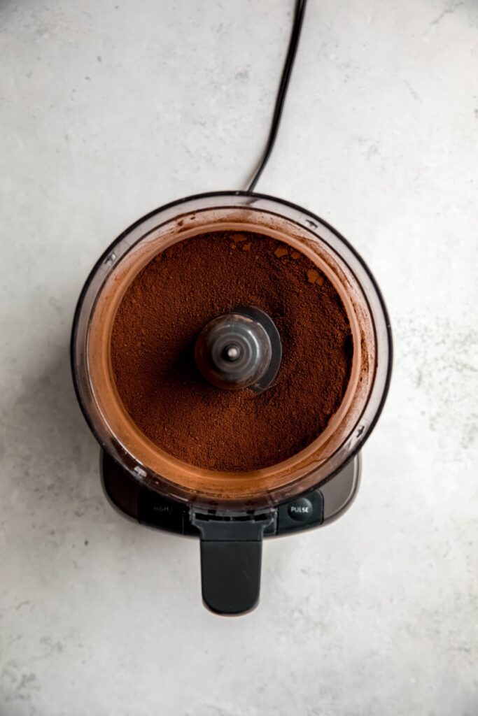 overhead shot of dark chocolate hot cocoa mix in the bowl of a food processor after blitzing together.
