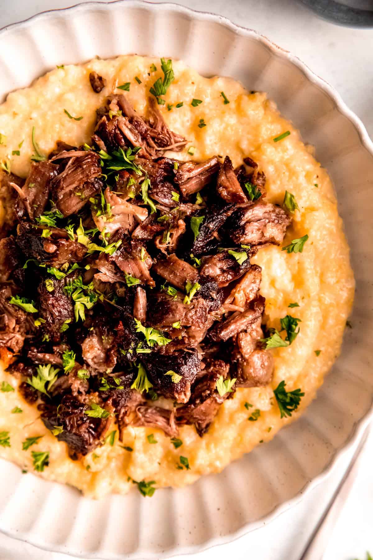 closeup overhead shot of red wine beef short ribs and cheesy polenta.