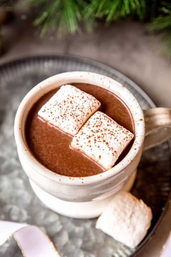 45 degree angle downward shot into a mug of spicy aztec sipping chocolate topped with marshmallows and a sprinkle of chili powder; you can see the chocolate mixture is quite thick.