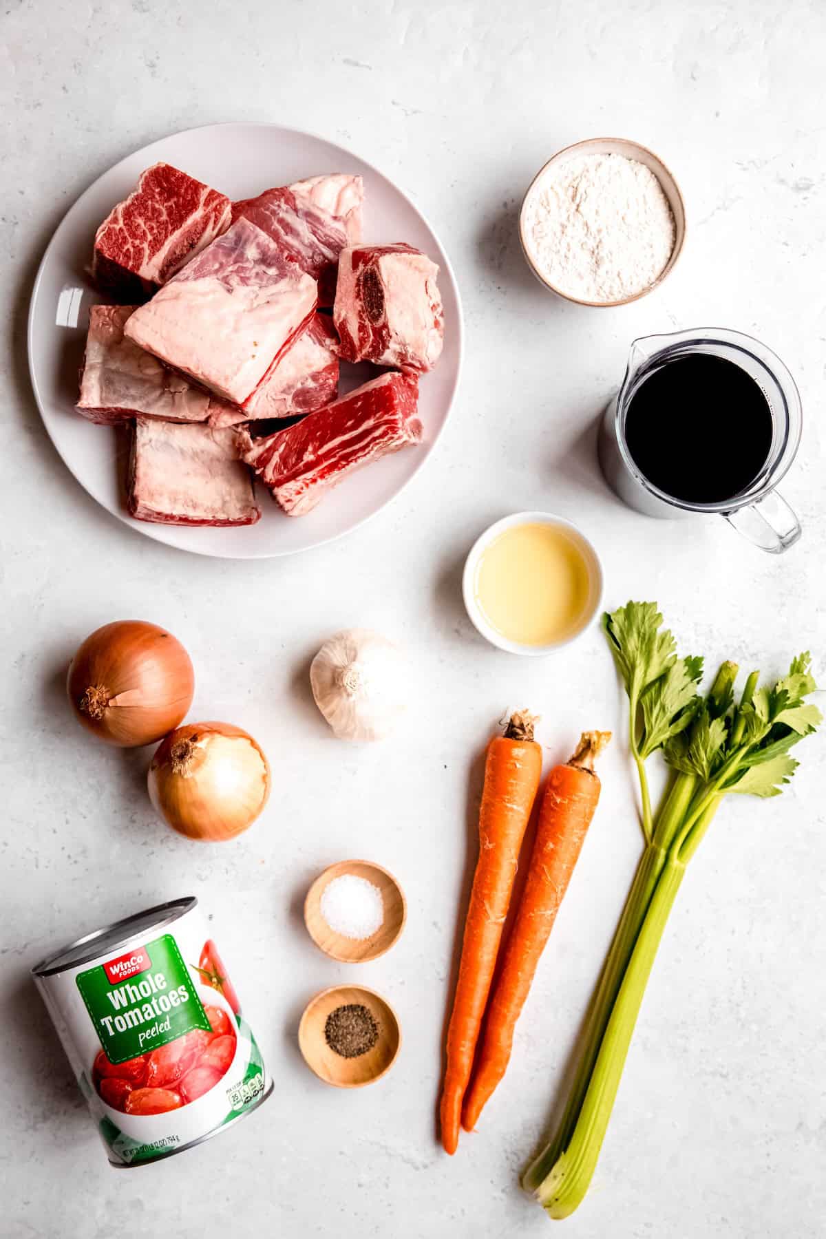 ingredients needed to make Italian-style red wine braised short ribs recipe measured out on a white table.