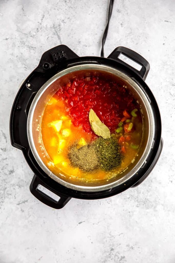 broth, canned tomatoes, chopped potatoes, and herbs & spices added to the instant pot with the sauteed mirepoix and garlic.