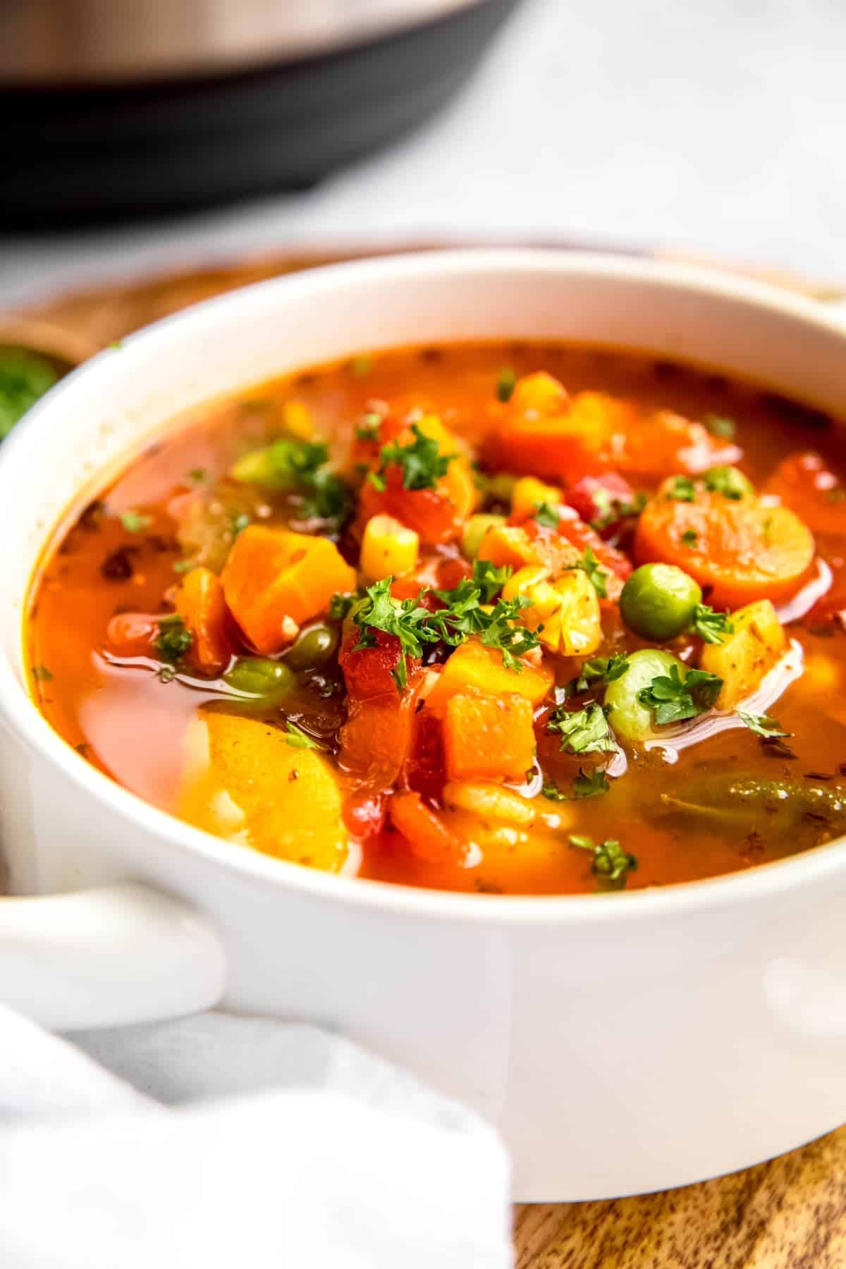 closeup 45 degree angle shot of instant pot vegetable soup with frozen vegetables showing the chunks of corn, tomatoes, peas, carrots, celery, green beans, and potatoes.