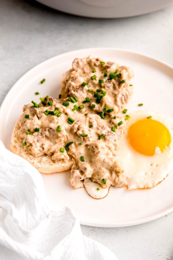 45 degree angle shot of a plate of breakfast sausage gravy and biscuits with a fried egg.