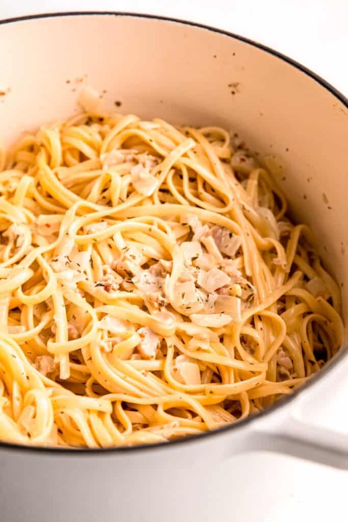 closeup shot of clam linguine with white wine sauce in a white dutch oven after tossing together.