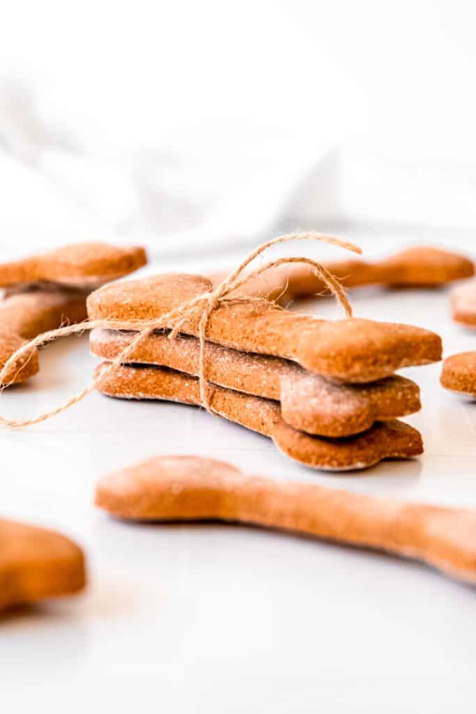 stack of three crunchy peanut butter banana dog treats shaped like dog bones tied with twine.