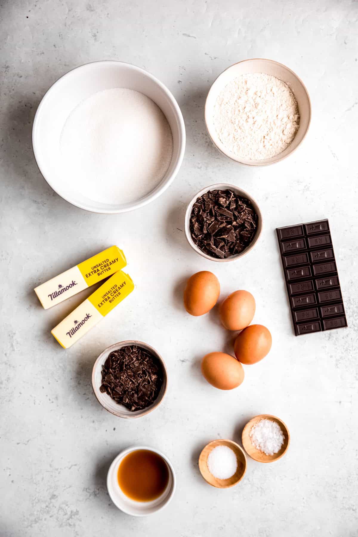 ingredients needed to make Julia Child's dark chocolate brownies recipe with the addition of dark chocolate chunks measured out on a white table.