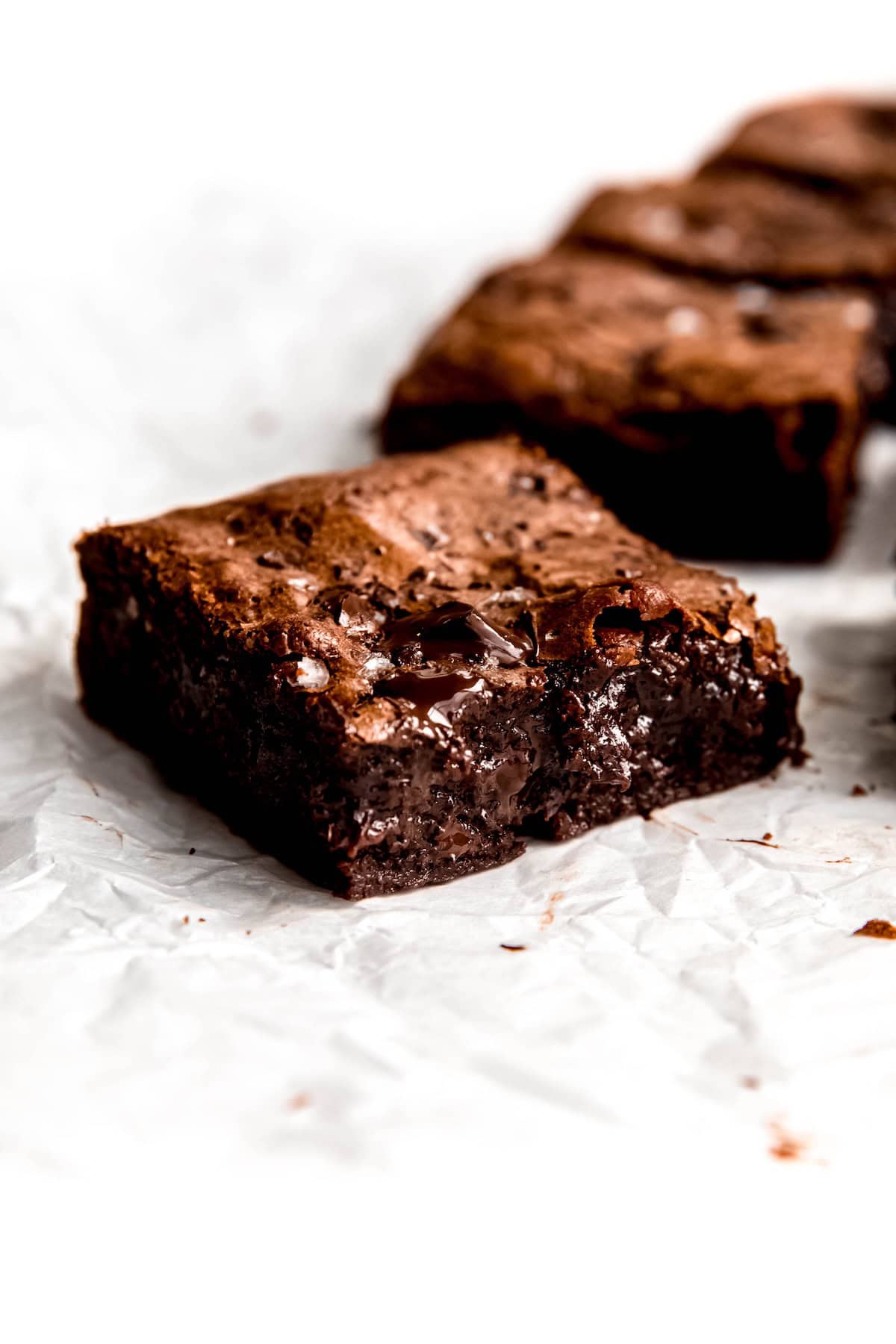 closeup shot of a single dark chocolate chip brownie showing the fudgy interior with melty chocolate pockets.