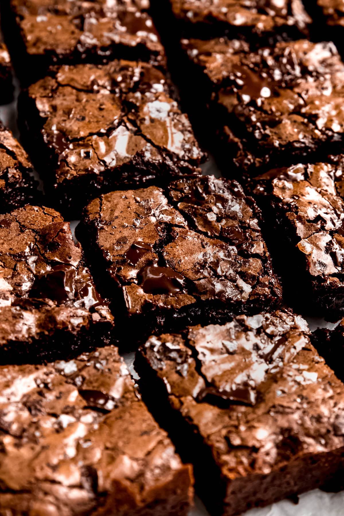 45 degree angle shot of extra fudgy brownies cut into squares; you can see the shiny crinkly top and the dark fudgy interior.