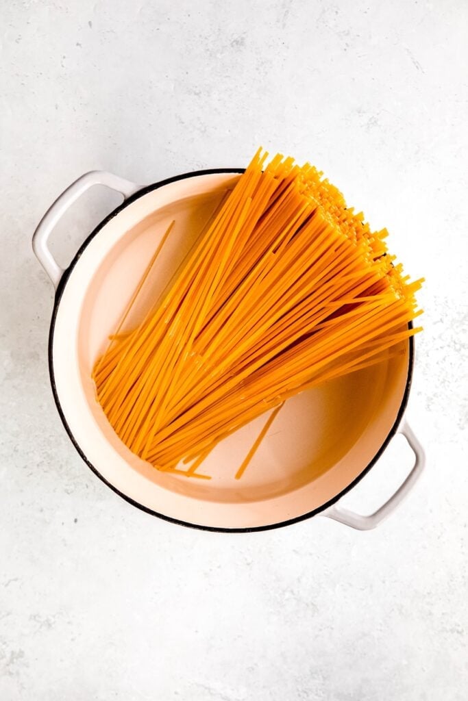 pasta added to a white dutch oven with salted water to boil.