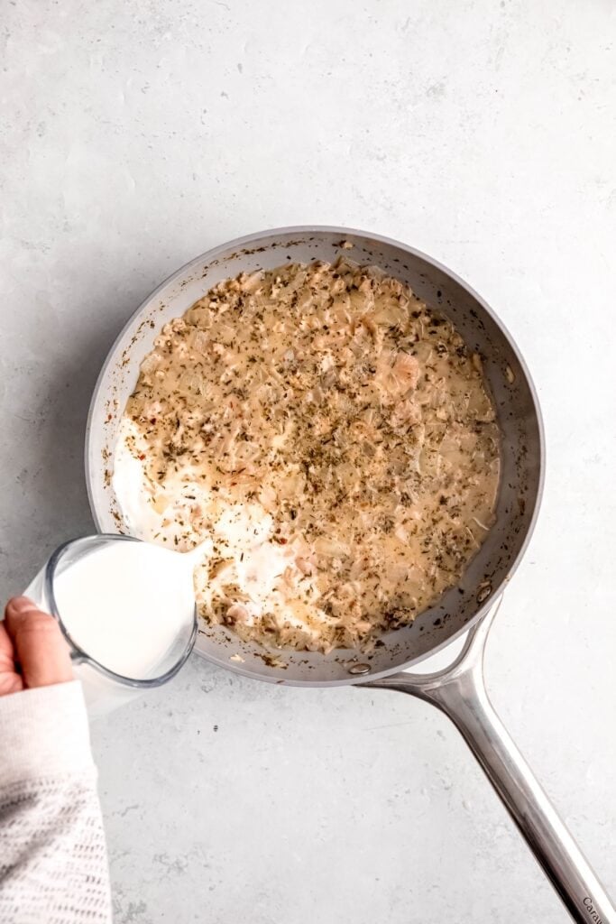 action shot of half & half being poured in the pan with the white wine clam sauce.
