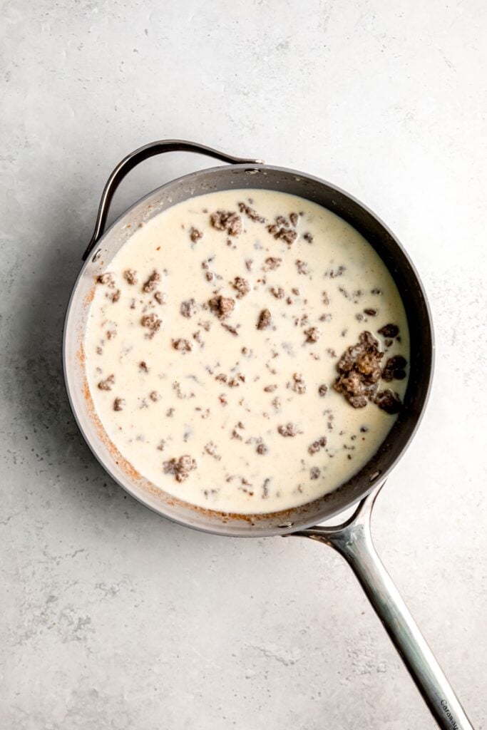 sausage gravy mixture after slowing incorporating the first cup of milk; there are large chunks of sausage poking through the top.