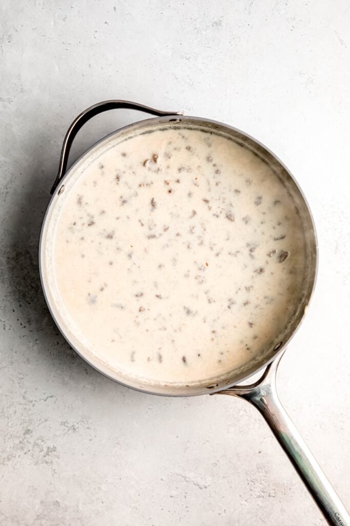 remaining milk added to the skillet; the sausage is slightly poking through, but the pan looks more white than before.