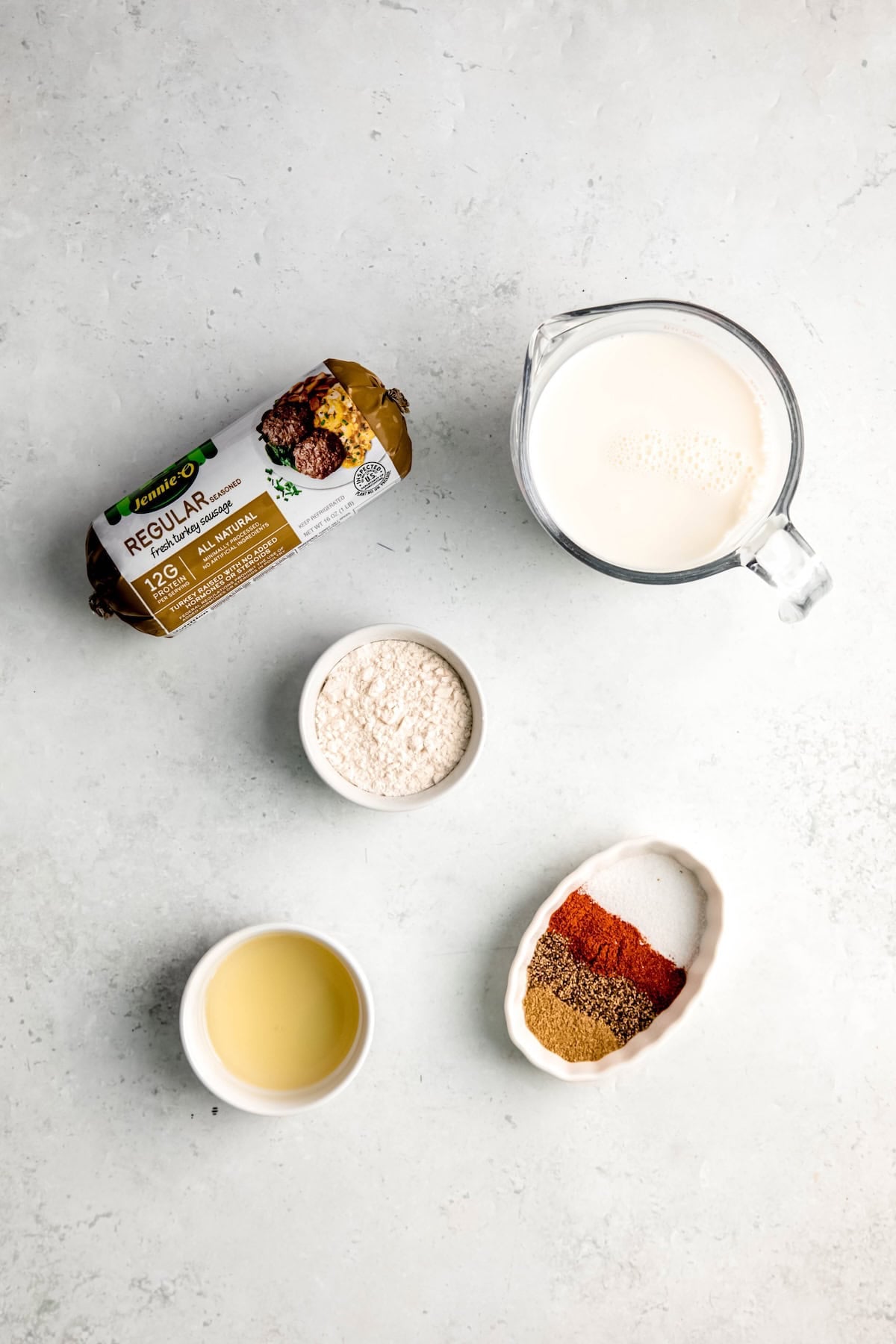 ingredients needed to make old fashioned sausage gravy recipe measured out on a white table.