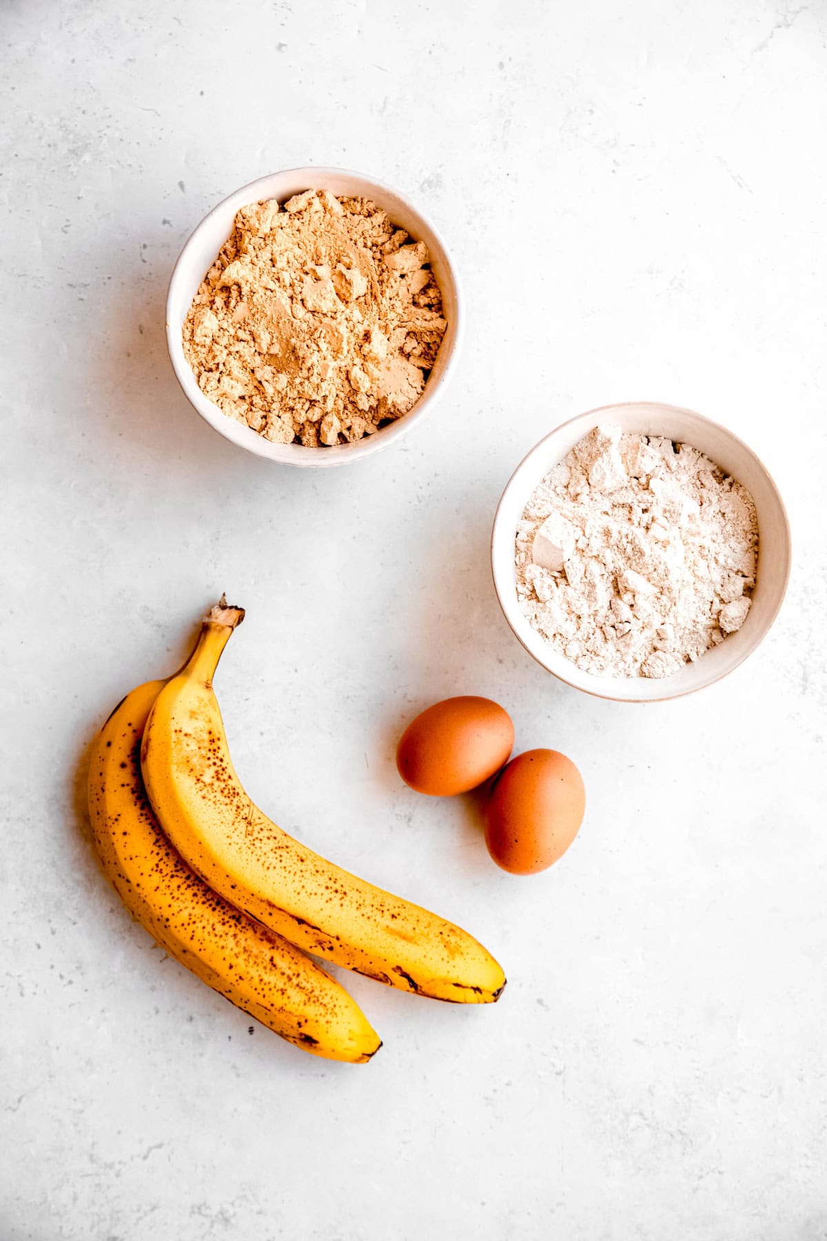 ingredients needed to make homemade peanut butter and banana dog treats recipe measured out on a white table.