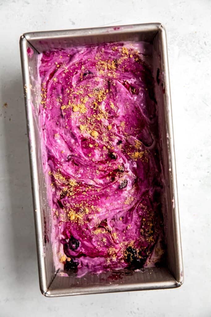 tin of blueberry cheesecake ice cream with a vibrant purple swirl and graham cracker crumbles.