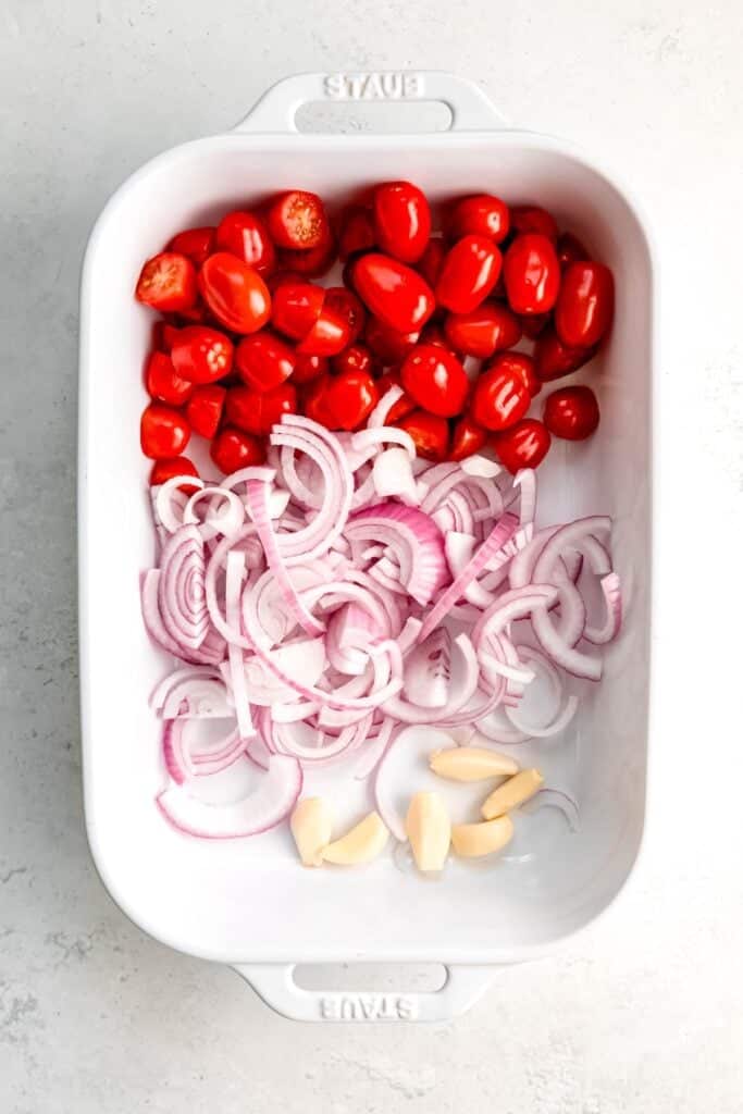 tomatoes, onions, garlic, and jalapenos added to a white 9x13 baking dish.