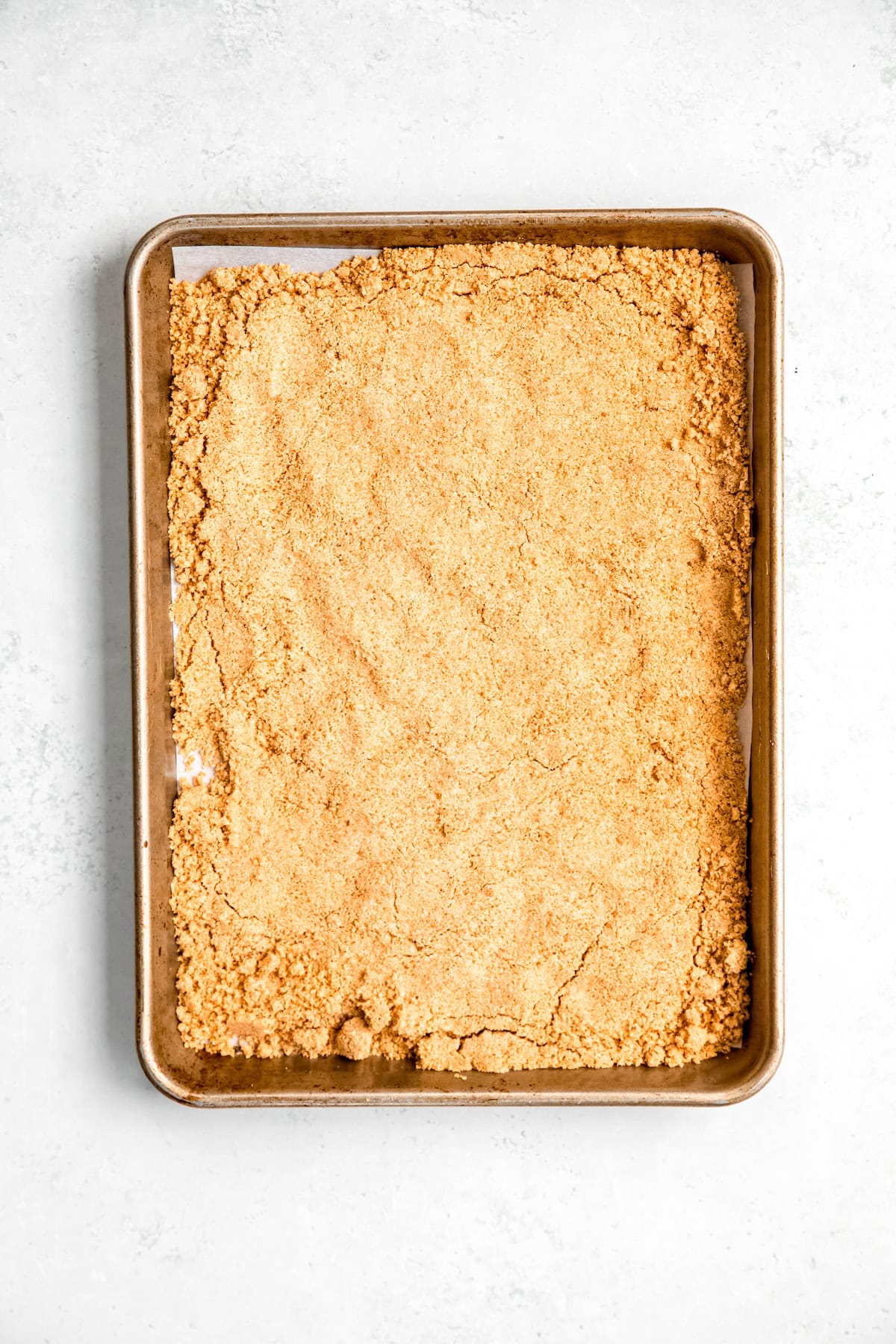 graham cracker crumble on a baking sheet after baking and flipping.