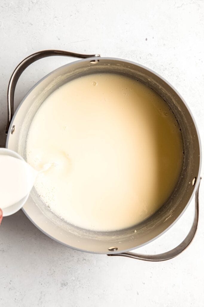 action shot of the slurry being poured into the cooked milk mixture.