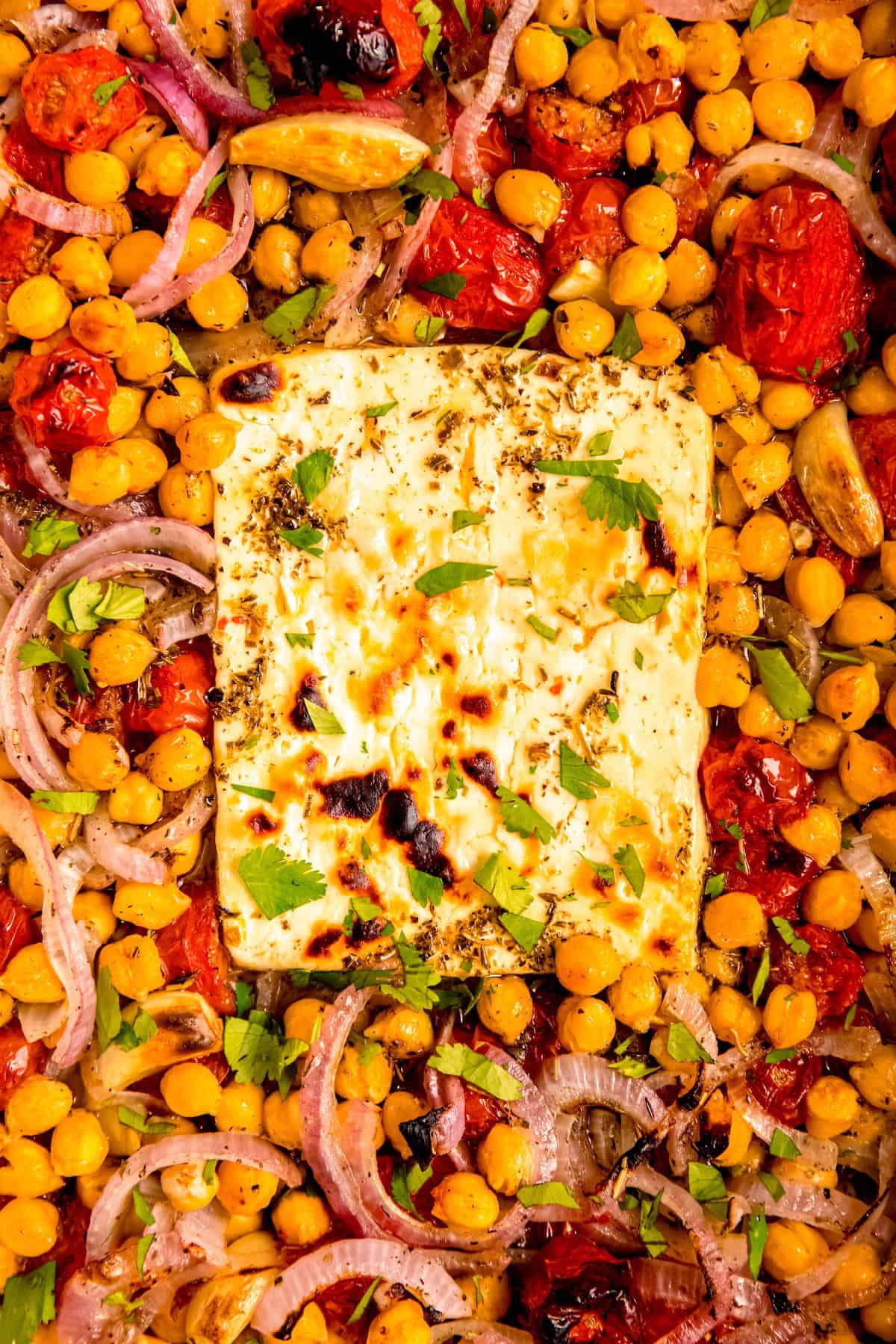 flat lay closeup shot of a tray of Mediterranean baked feta and tomatoes with chickpeas.