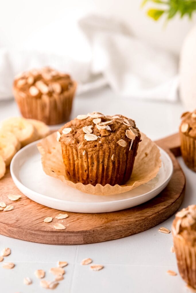 easy healthy banana bread muffins with rolled oats and whole wheat on a white table with sliced bananas.