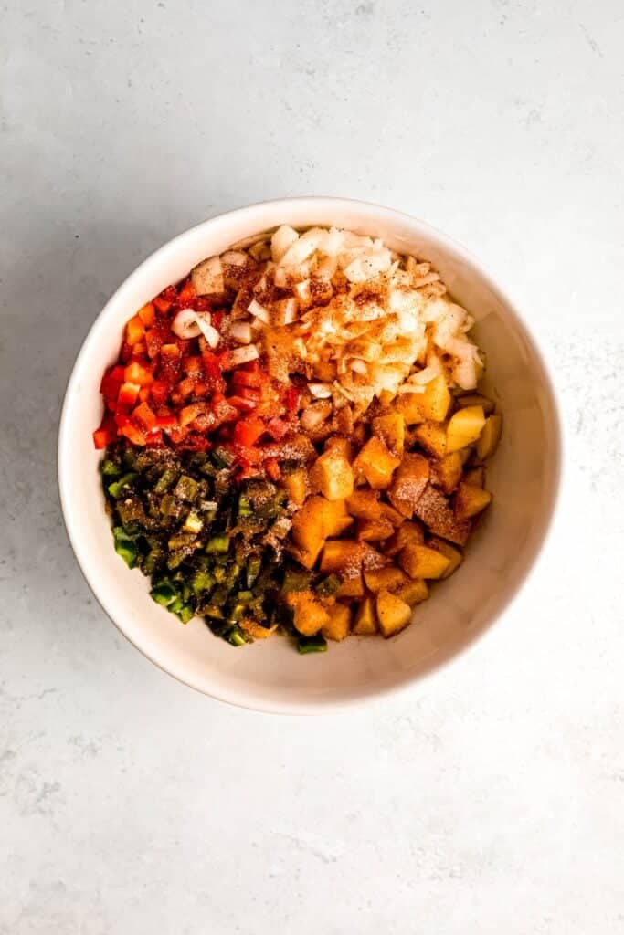 all home fries ingredients added to a mixing bowl.