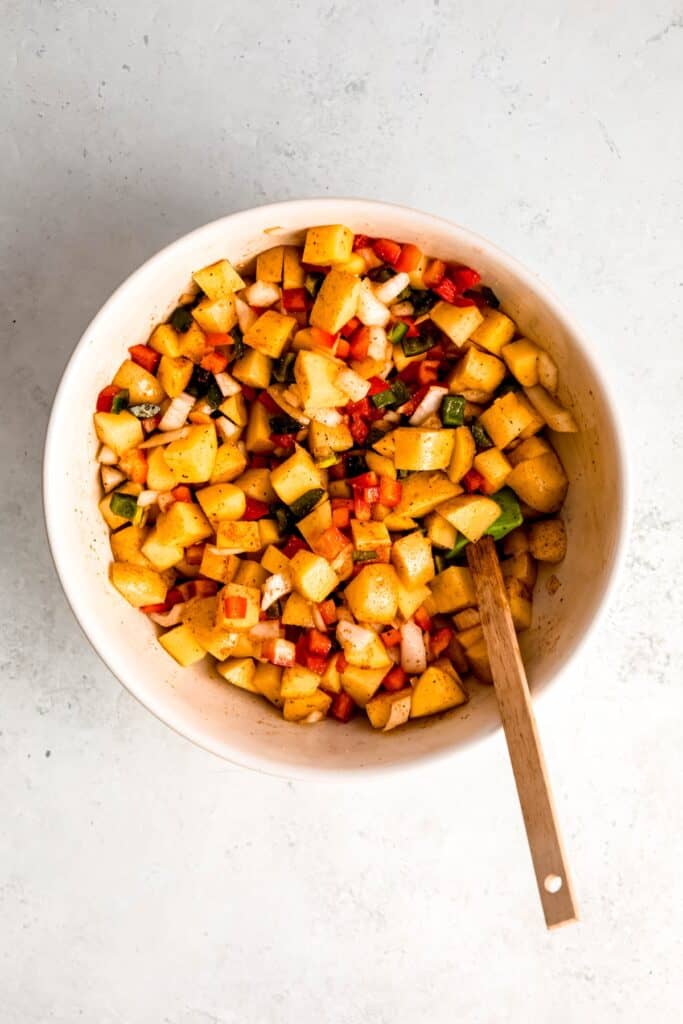 home fries ingredients after tossing together in a mixing bowl.