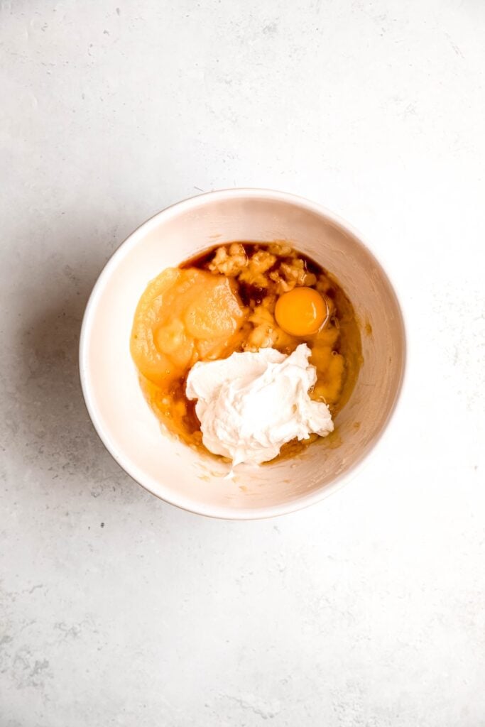 yogurt, egg, applesauce, and vanilla added to the bowl with the mashed bananas.