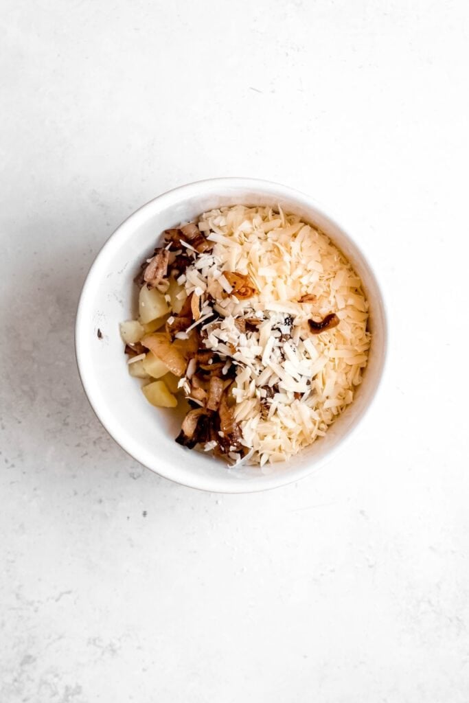 potato and cheese filling ingredients added to a mixing bowl.