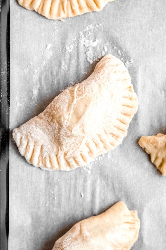 potato and cheese pierogi on a baking sheet after filling and crimping.
