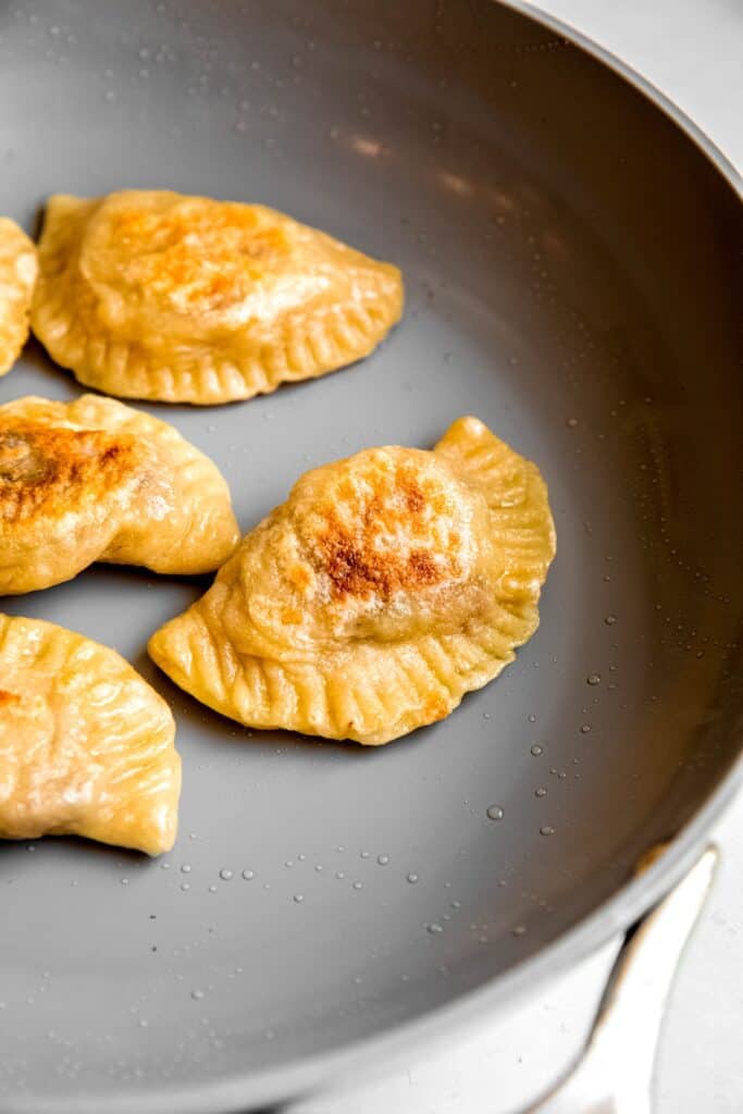 non-stick pan with boiled pierogi pan frying till golden.