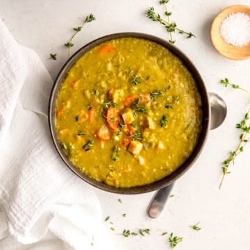 square hero image of a bowl of instant pot split pea ham soup on a white table.