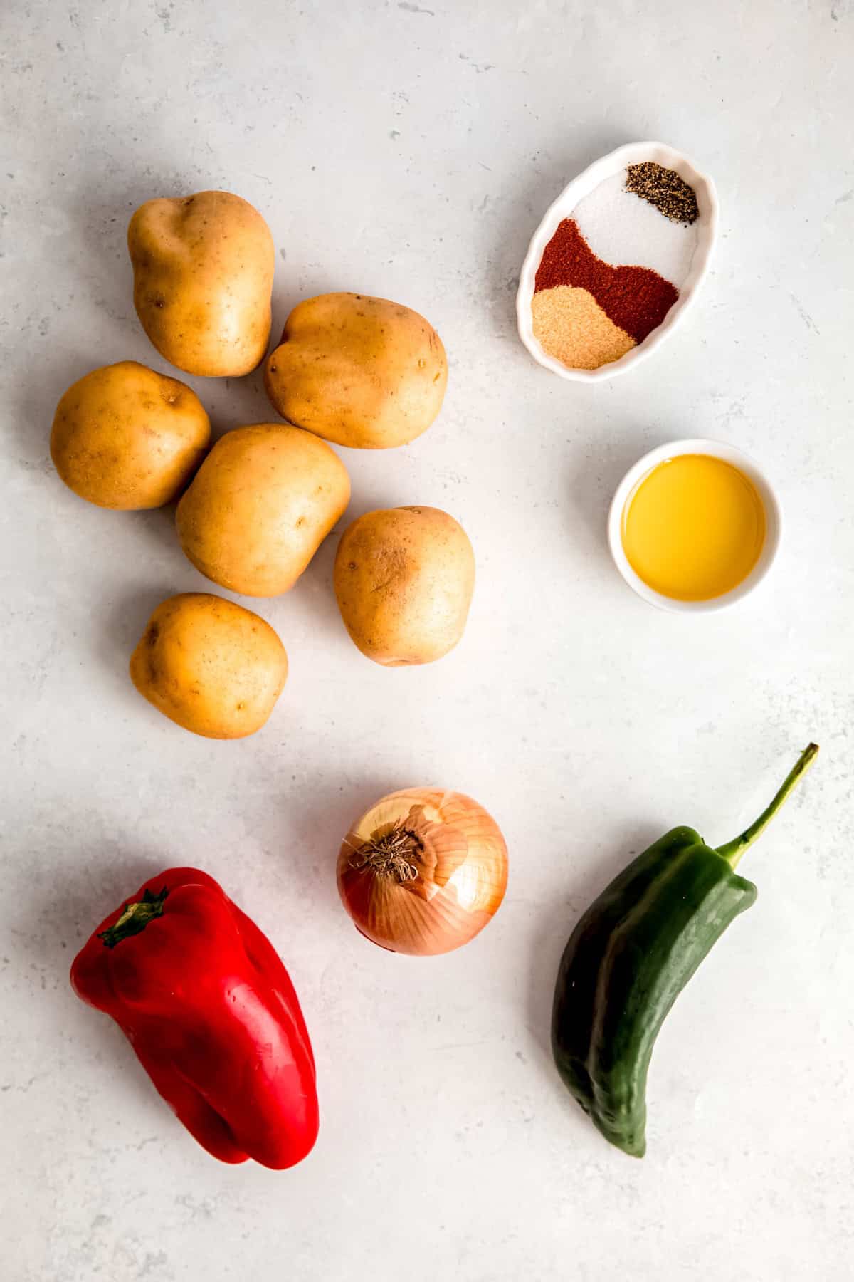 ingredients needed to make baked home fries measured out on a white table.