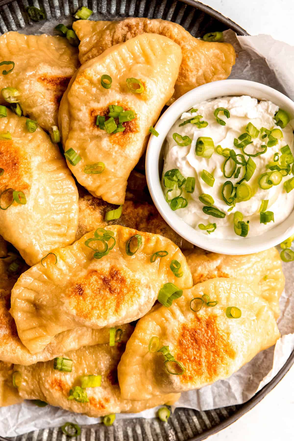 overhead shot of a platter of potato and cheese pierogi after pan frying till golden brown.