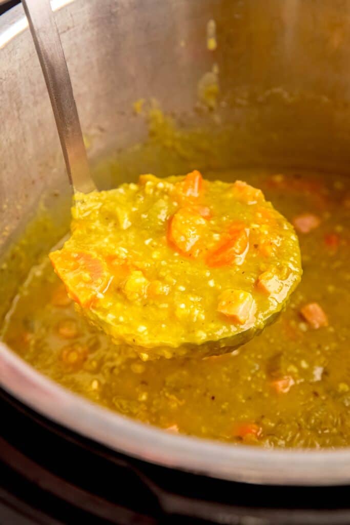 silver ladle taking a portion of split pea soup from the instant pot insert.